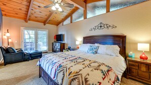 A spacious bedroom with a large bed, a wooden ceiling, and a TV on a stand. - Stunning Idyllwild Home w/ Private Hot Tub & Decks (Idyllwild)