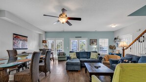 A spacious living room with a glass dining table, comfortable seating, and a ceiling fan. - Beautiful, clean and spacious dog friendly beach home! Special summer rates! (SURFSIDE BEACH)