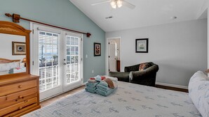 A bedroom with a bed, a dresser, a chair, and a door leading to a balcony. - Beautiful, clean and spacious dog friendly beach home! Special summer rates! (SURFSIDE BEACH)