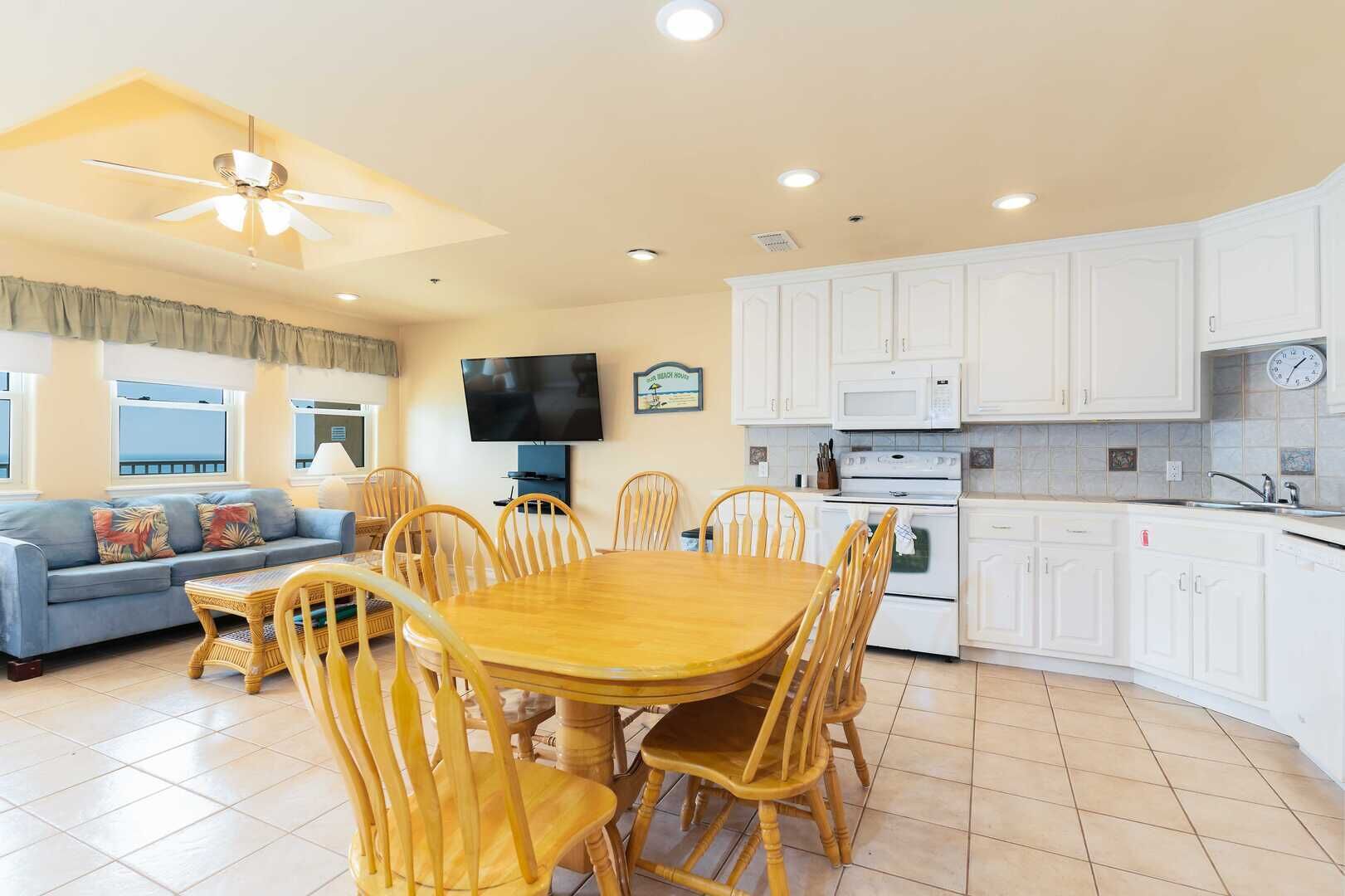 A spacious living area with a dining table, chairs, a sofa, and a TV.