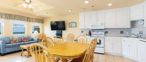 A spacious living area with a dining table, chairs, a sofa, and a TV.