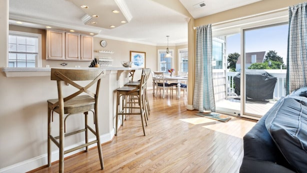 A spacious kitchen with wooden cabinets, a dining area with a table and chairs, and a large sliding glass door leading to a balcony. - Entire Home w/ pool, walk to beach (Virginia Beach)