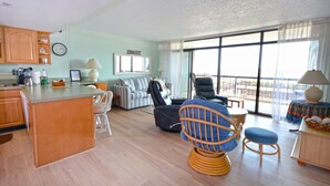 Amplia sala de estar con cocina, comedor y balcón con vistas.