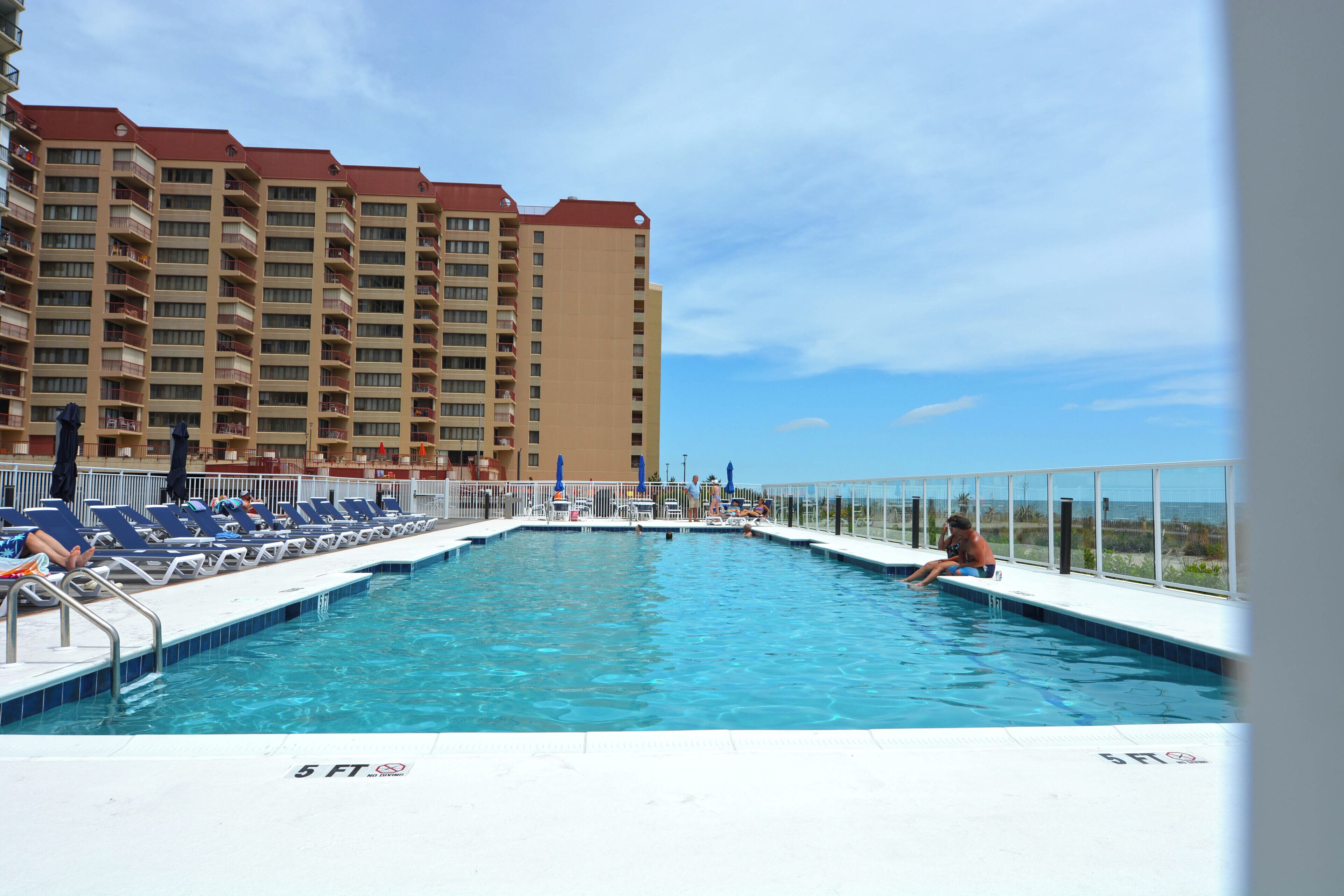 Una piscina con sillones de descanso y vistas a un rascacielos.