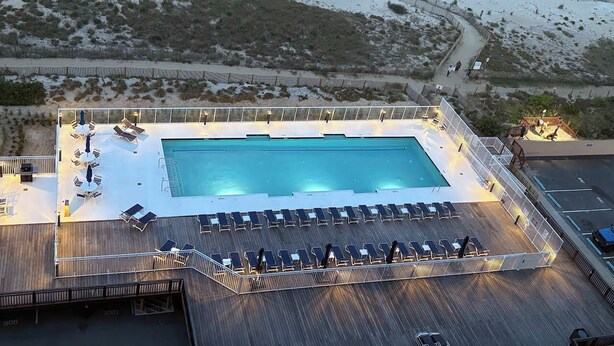 Vista aérea de un resort con piscina, tumbonas y zona de playa.