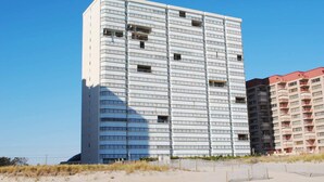 Un hotel de varios pisos con un diseño moderno, que presenta una cuadrícula de balcones y un techo plano.