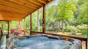 Jacuzzi en una terraza de madera con vista a un área boscosa.