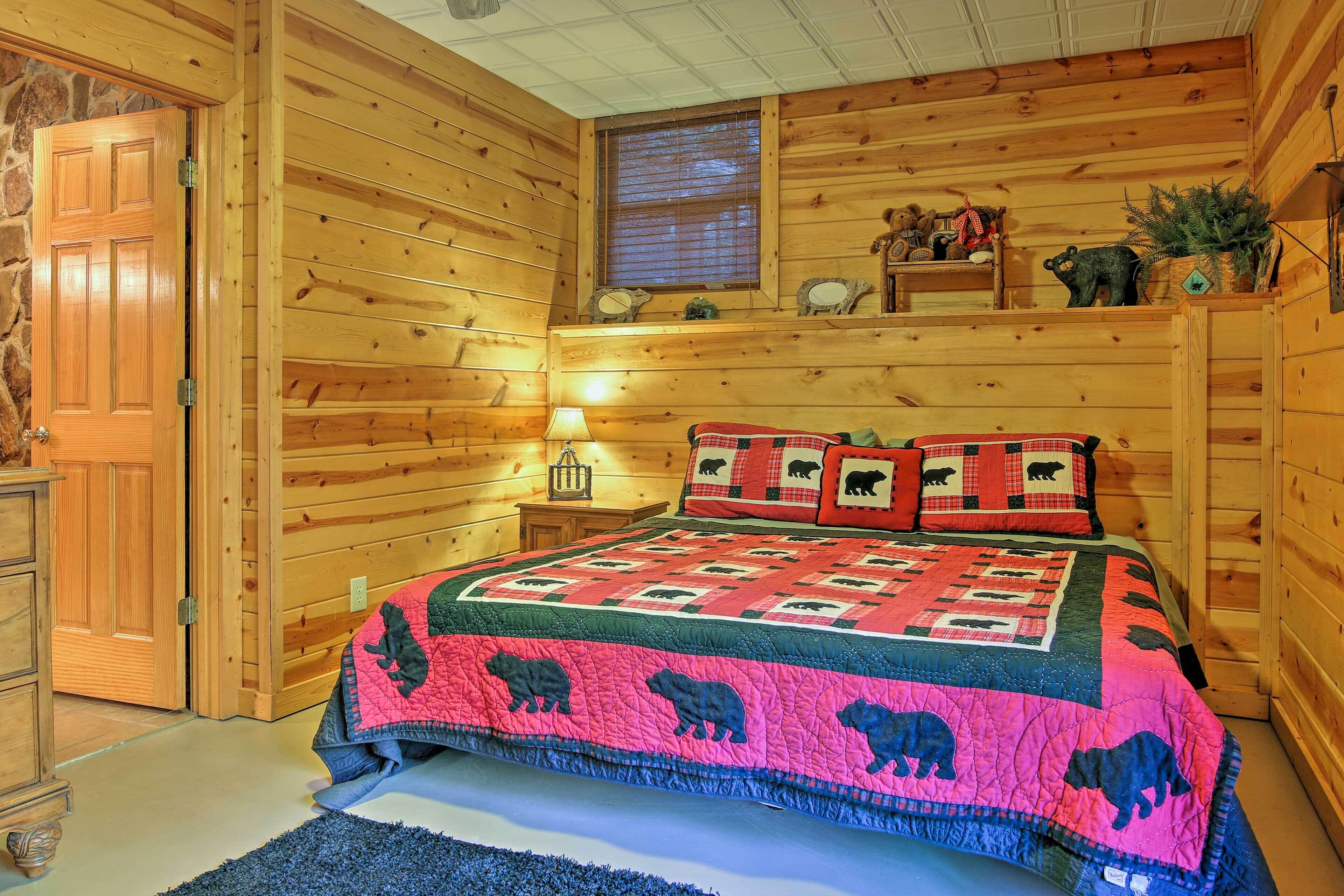 A wooden cabin bedroom with a bed, a nightstand, a lamp, and a window with blinds.