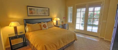 A hotel room with a bed, two bedside tables with lamps, a ceiling fan, and a large window with a view.