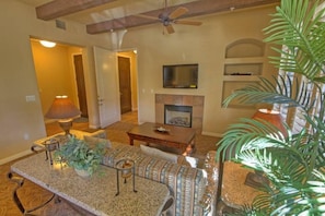 A living room with a fireplace, a television, and a ceiling fan.