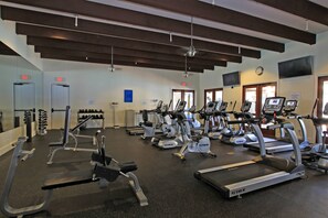 A gym with multiple treadmills, weight machines, and a clock on the wall.