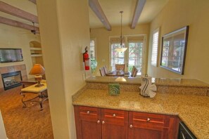 A kitchen with granite countertops, wooden cabinets, a fireplace, and a dining area with a table and chairs.