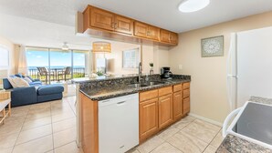A modern kitchen with wooden cabinets, a dishwasher, and a granite countertop. - Seaside Luxury Private Balcony, Breathtaking Views & Steps to the Sand (Cape Canaveral)