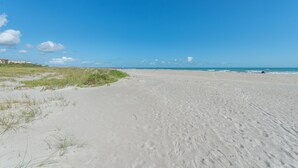 A wide sandy beach with gentle waves and a clear blue sky. - Seaside Luxury Private Balcony, Breathtaking Views & Steps to the Sand (Cape Canaveral)