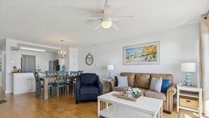 Een woonkamer met een bank, salontafel en een eetgedeelte met stoelen en een tafel.