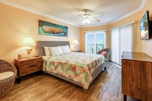 A bedroom with a bed, nightstands, a wicker chair, a wooden dresser, and a ceiling fan. - Land's End 303 building 6 Gorgeous 3rd floor remodeled beach front condo! (Treasure Island)