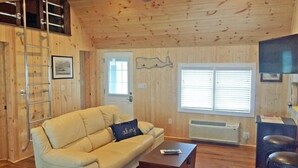 Een gezellige woonkamer met een beige bank, een houten salontafel en een plafondventilator.