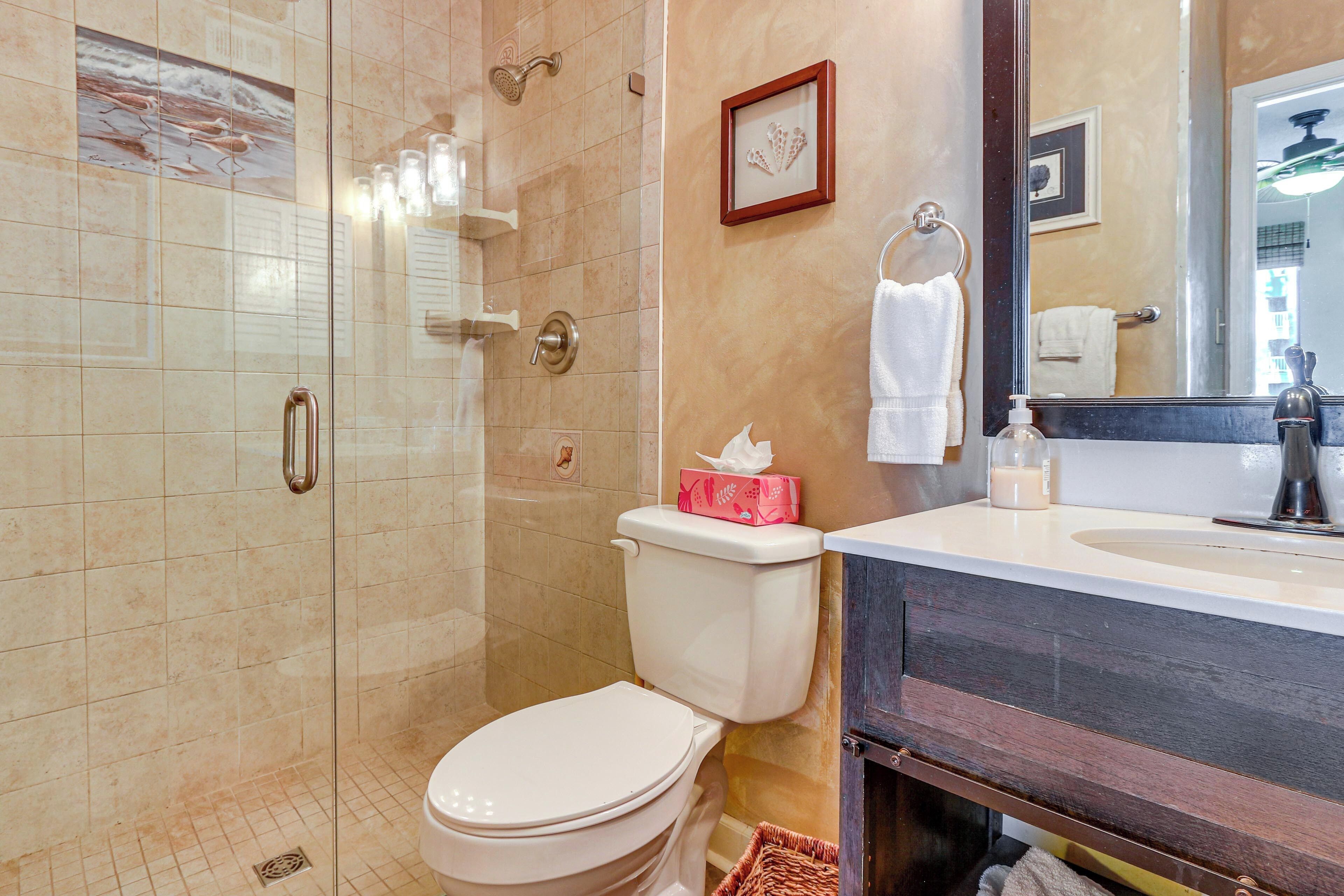 A bathroom with a shower, toilet, and vanity with a mirror.