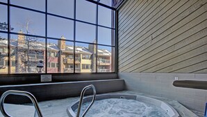A hot tub area with a view of buildings through large windows.