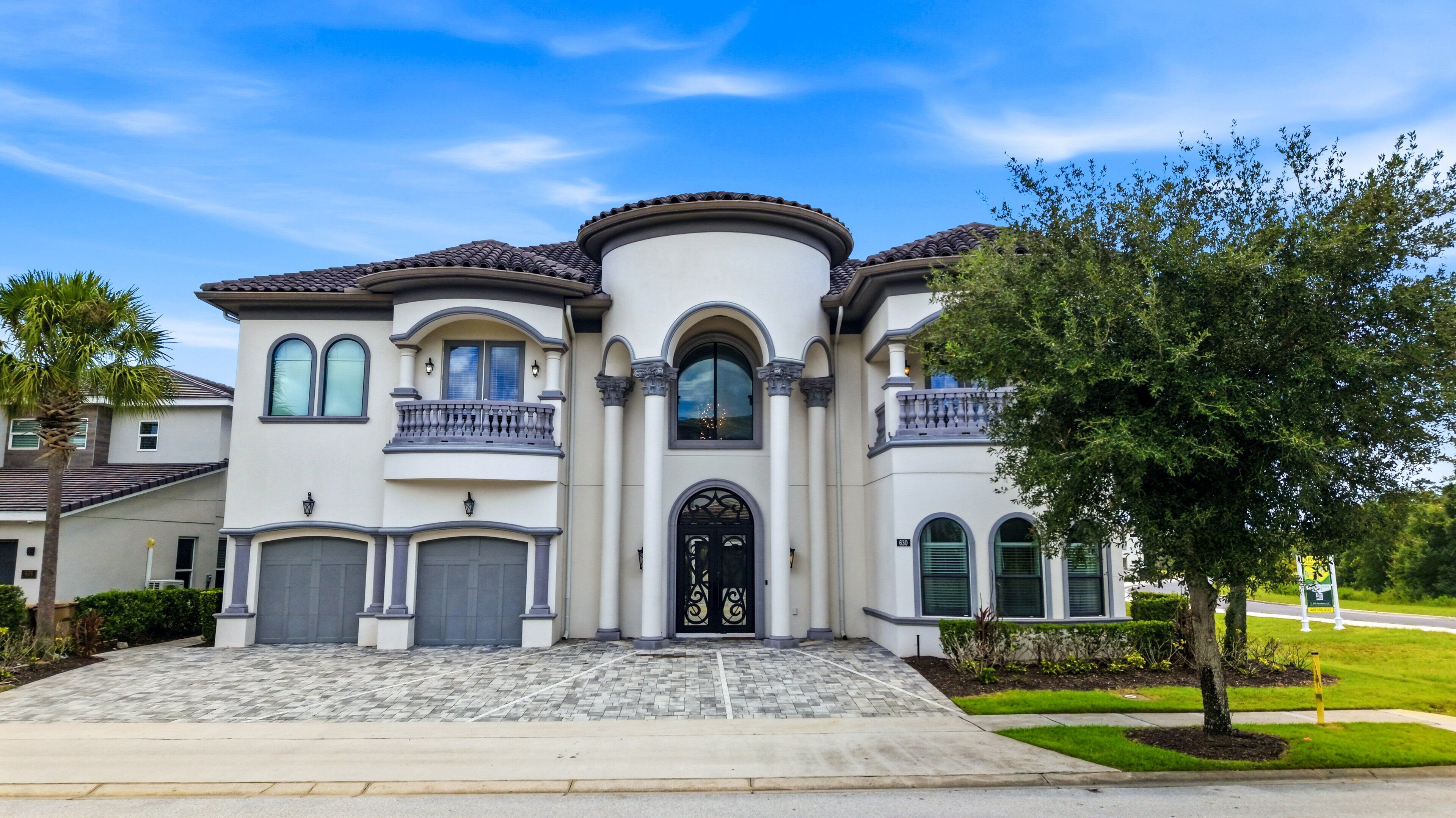 A two-story house with a symmetrical facade, a central entrance with a decorative door, and a balcony on the upper floor.