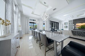 A modern kitchen with a large island, bar seating, and a dining area with a long table and chairs.