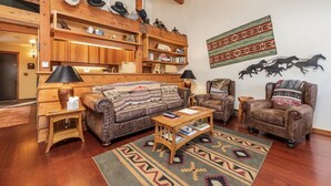 Un salón acogedor con una estantería de madera, sofás de cuero y una alfombra estampada.