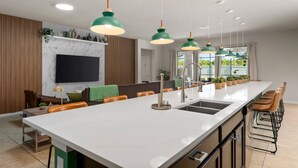 A modern kitchen with a large island, pendant lights, and a built-in TV.