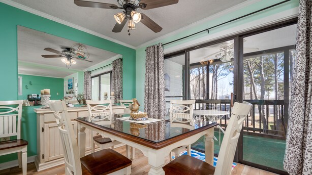 A dining area with a glass-top table, white chairs, and a ceiling fan. - Peaceful Bay Side Retreat with Large Pool perfect for a family vacation (Ocean City)