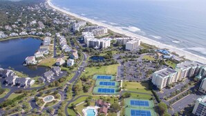 Luchtbeeld van een kustresort met meerdere gebouwen, een strand en een meer.