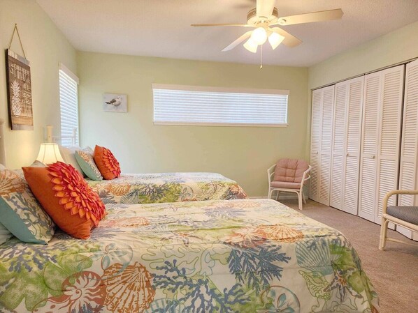 A bedroom with two beds, a ceiling fan, a window with blinds, a chair, and a closet. - Marsh View Villa #9 in Litchfield By The Sea w/ 3BR/2BA (Pawleys Island)