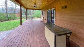 Um deck coberto com área de bar, mesas ao ar livre e vista da paisagem circundante.