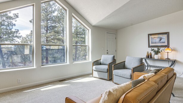 A spacious living room with large windows, a ceiling fan, a sofa, two armchairs, and a small table with a lamp. - Secluded Boulder House - Next to National Forests! (Boulder)