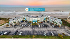 A beachfront building with a parking lot and a view of the ocean.
