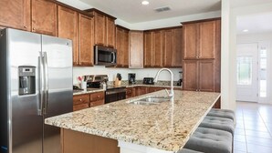 Eine moderne Küche mit Granit Arbeitsplatten, Edelstahlgeräten und Holzschränken.