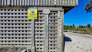 Ein Holzzaun mit einem Schild, das "Vacation Here!" zeigt, und einer Plakette mit den Aufschriften "WELCOME" und "ROSE".