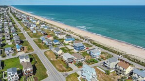 Luftaufnahme eines Küstenwohngebiets mit Häusern, Straßen und einem Strand.