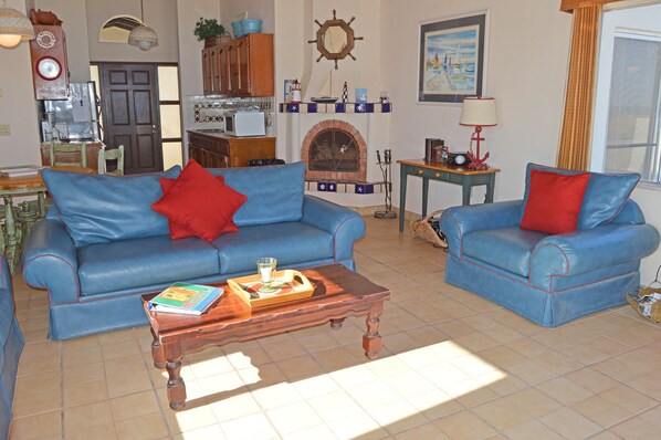Una sala de estar con dos sofás azules, una mesa de centro de madera y una chimenea.