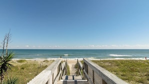 A wooden boardwalk leading to a beach with clear skies.