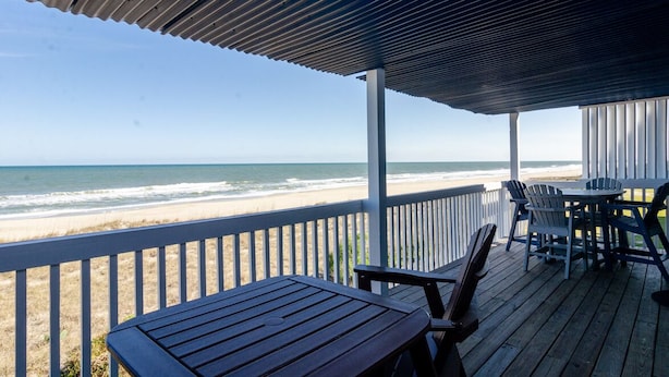 A wooden deck with a view of the beach and ocean.