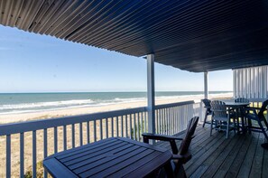 Una terraza de madera con vista a la playa y al océano.