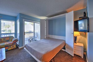 Une chambre à coucher avec un lit, une table de chevet, une télévision, une fenêtre et un balcon.