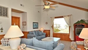 A living room with a ceiling fan, two sofas, a TV, and a window with curtains. - OH1213- Just 300 Feet to Beach, 4 BRs, Ocean/Lighthouse Views, Dog Friendly! (Corolla)