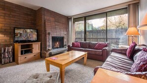 A living room with a brick fireplace, a television, a sofa, and a coffee table.