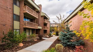 A multi-story residential building with balconies, a landscaped courtyard, and a clear sky.