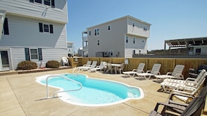 A swimming pool with lounge chairs and a wooden fence. - KH4004- Oceanside-5 BRs, Elevator, Pool Table, Private Pool and Hot Tub! (Kitty Hawk)