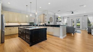 A spacious kitchen with a large island, wooden flooring, and modern cabinetry. - Polished Villa with Home Theater at Reunion (Kissimmee)