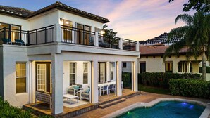 A two-story house with a swimming pool, outdoor seating, and a balcony. - Polished Villa with Home Theater at Reunion (Kissimmee)