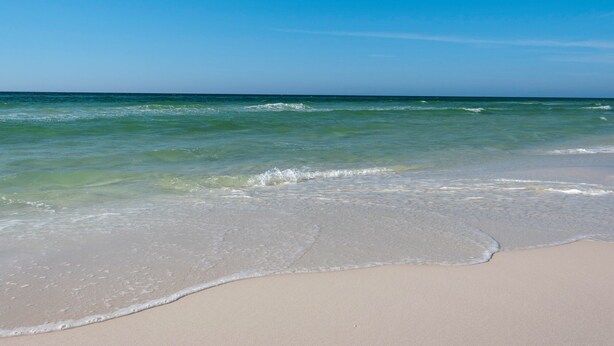 A beach with clear blue water and a sandy shore. - Comfortable Townhome with a Short Walk to Community Pool and the Beach! (Miramar Beach)