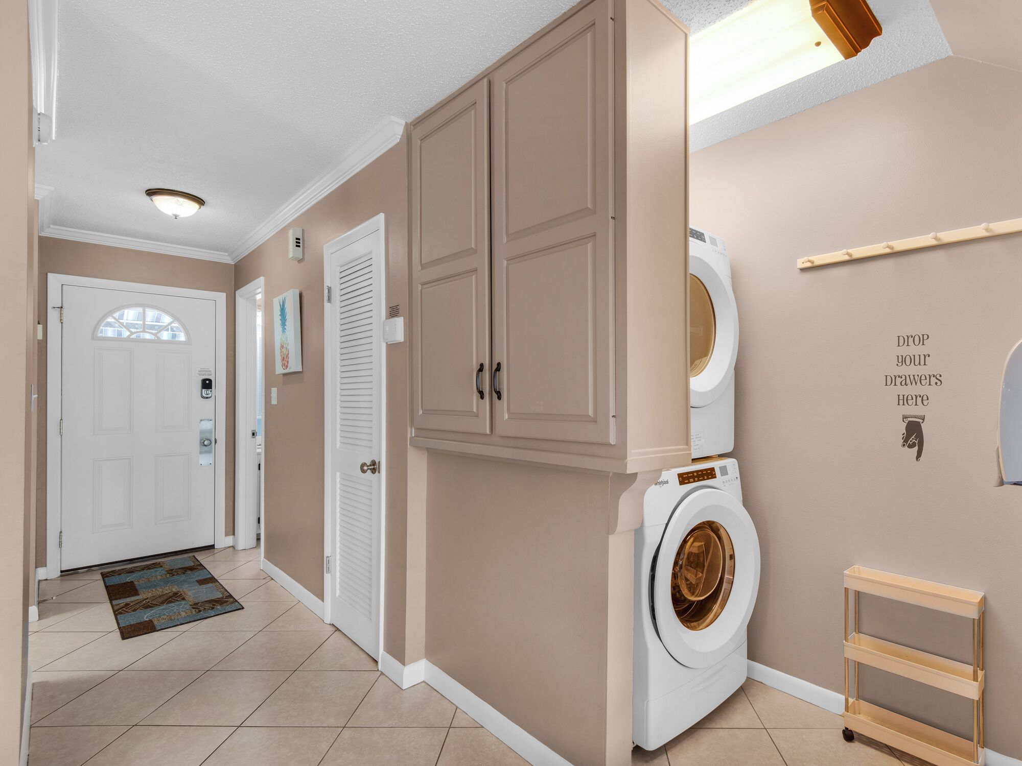 A laundry room with a washing machine, cabinets, and a sign indicating where to drop off laundry.