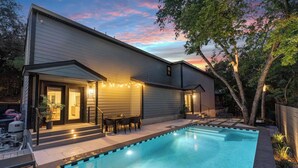 A modern house with a swimming pool, outdoor seating, and string lights. - Designer Duplex | Pool, Fire Pit, Near UT Football (Austin)